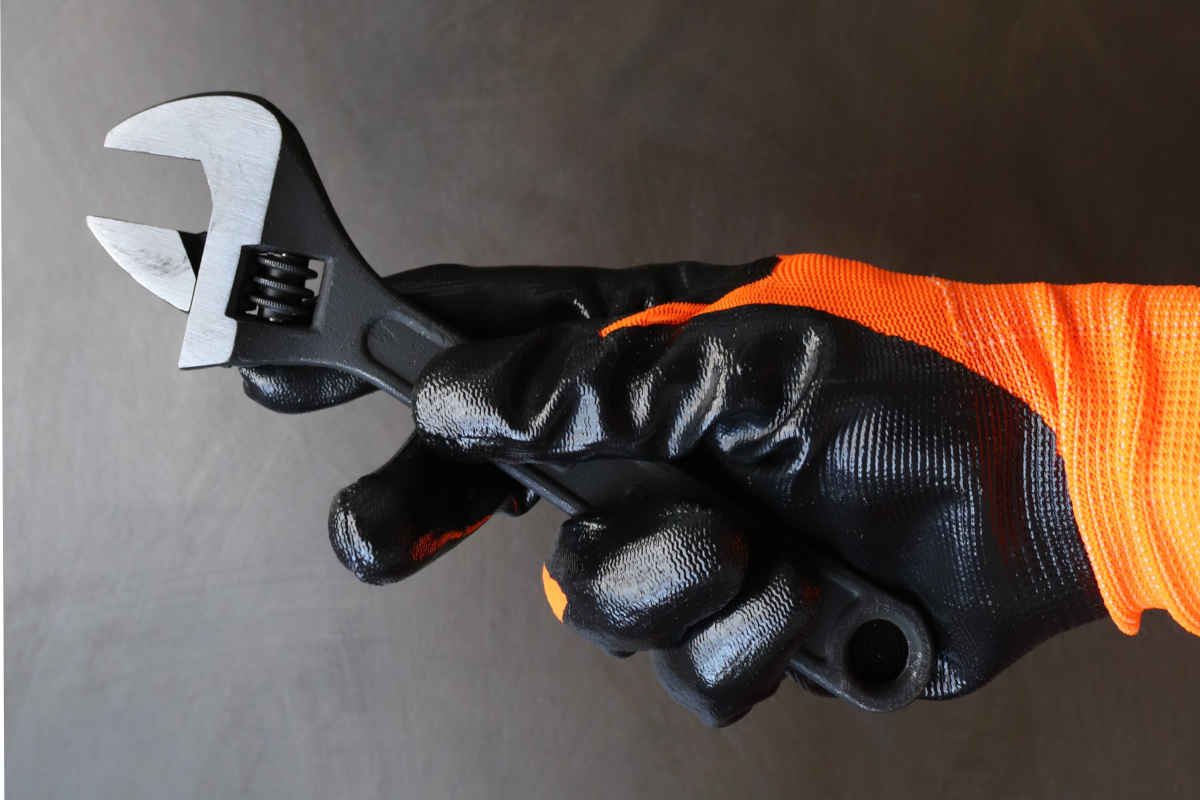 mano protegida con guantes de protección mecánica sujeta llave inglesa