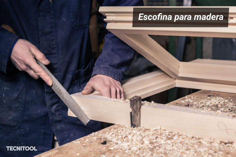 Carpintero rebaja el bastidor de una ventana con escofina para madera en el banco del taller