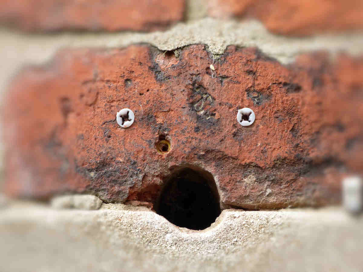 Una cara en una pared de ladrillo: el orificio es la boca y los tacos son los ojos