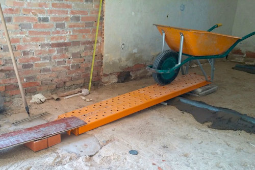 Carretilla de obra estrecha usada para cargar mortero de cemento en una reforma de interior.