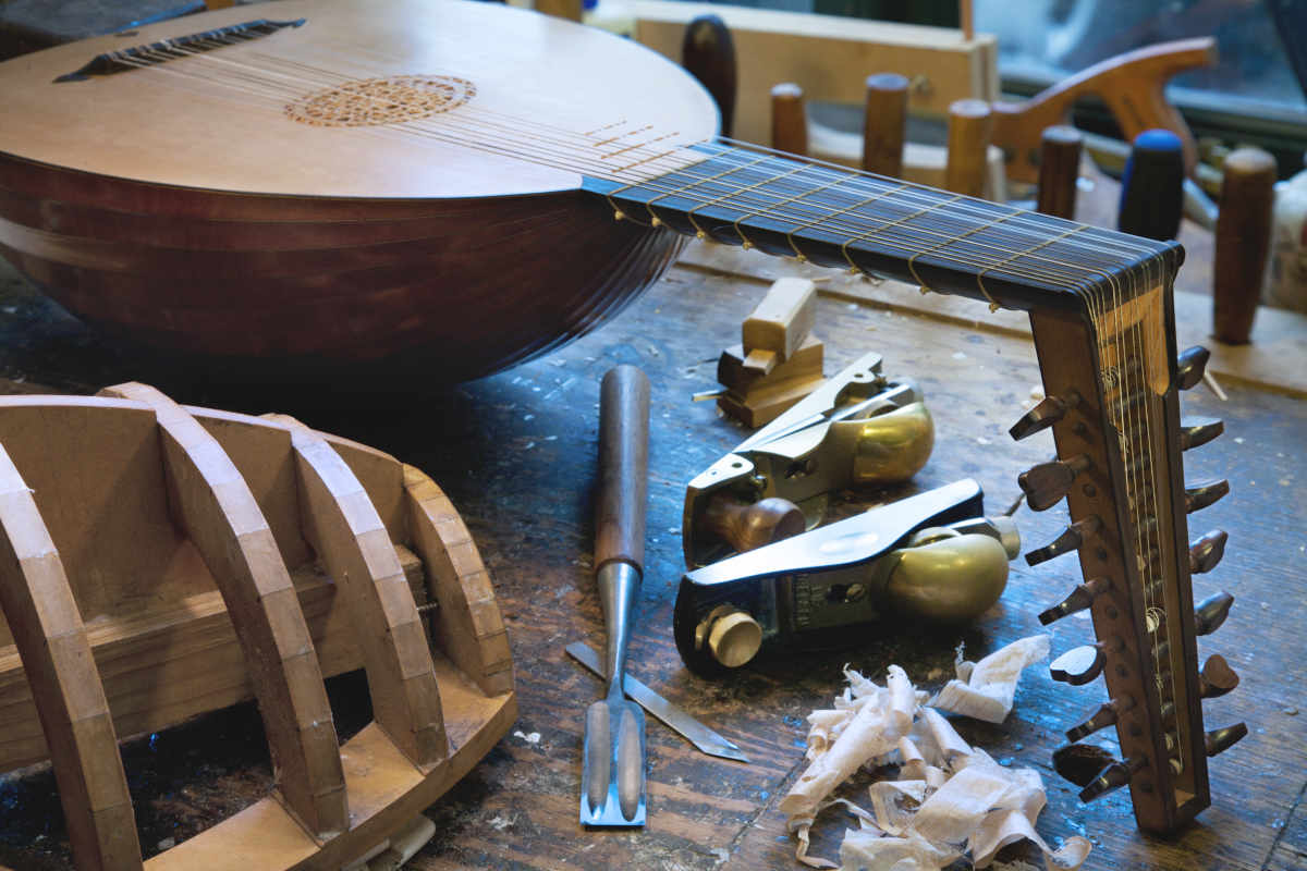 Herramientas de lutier en un taller junto a un laúd
