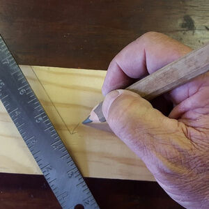 mano experta de un carpintero tomando medidas en una madera con la regla y el lápiz