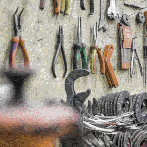 panel de un banco de trabajo del que cuelgan herramientas de anclar, sujetar y fijar como alicates y pinzas