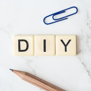 palabra «DIY» formada con las piezas del juego de mesa scrabble junto un lápiz a modo de ejemplo de blogs y publicaciones sobre bricolaje