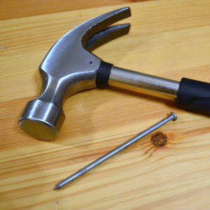 martillo de carpintero junto a una punta larga de acero