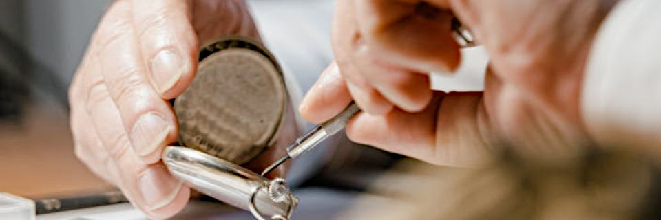 un relojero repara un reloj con un destornillador de precisión